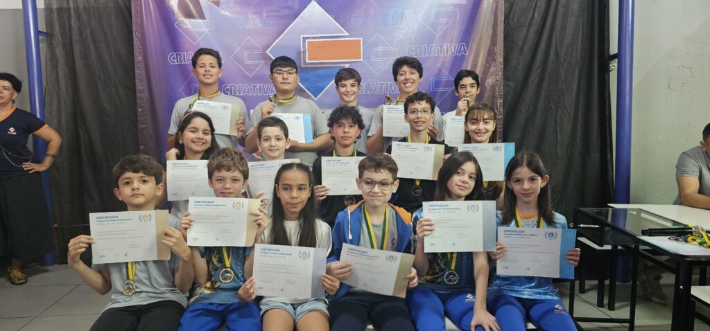 Alunos da Escola Criativa exibem medalhas e certificados durante cerimônia de premiação.